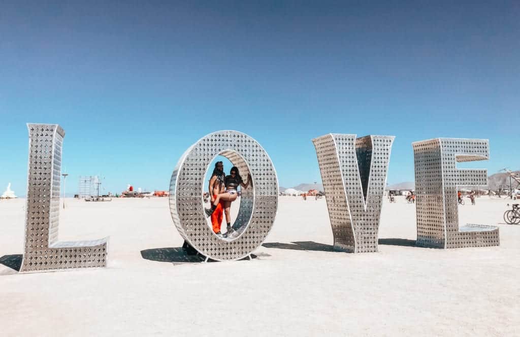 two people inside the "Love" sculpture by Laura Kimpton at Burning Man